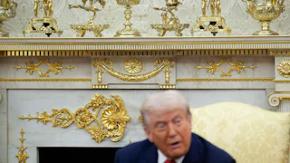 Trump sits in front of gold decor in oval office
