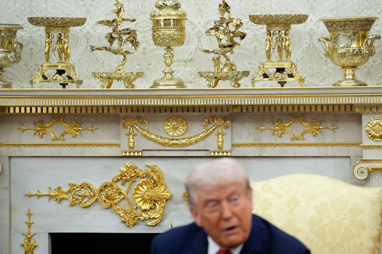 Trump sits in front of gold decor in oval office