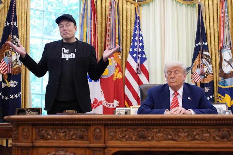 Elon Musk shrugs while standing next to Donald Trump, who sits at his desk in the Oval Office