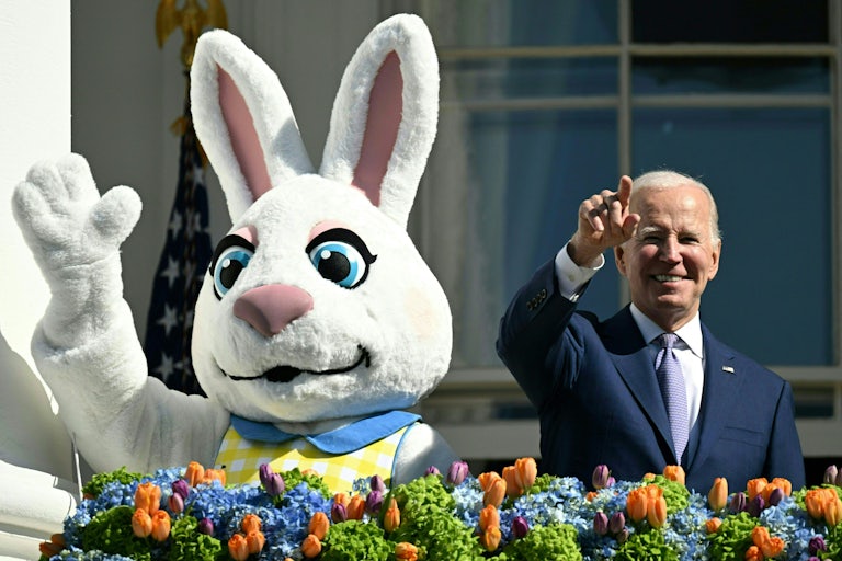Joe Biden points while standing next to an Easter Bunny, who is waving