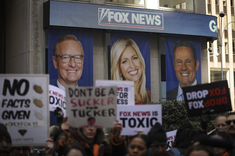 Protestors wave signs while gathering outside of Fox News' New York City headquarters.