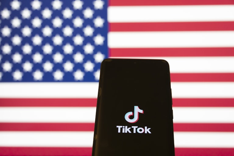 A phone screen displays the TikTok logo. An American flag is behind the phone.