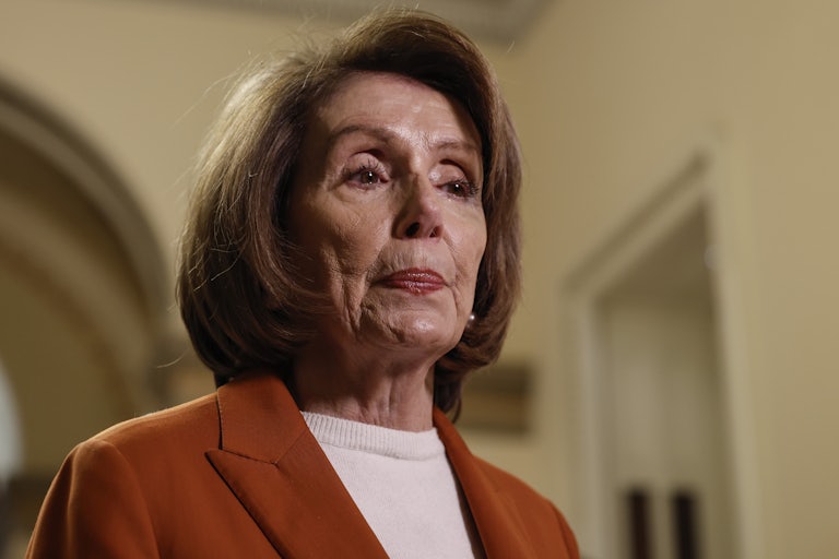 Nancy Pelosi looks down, lips pursed.