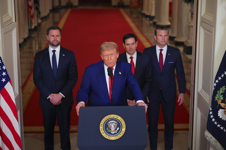 Donald Trump speaks at a podium after airstrikes on Iran. He is flanked by Vice President JD Vance, Secretary of State Marco Rubio, and Secretary of Defense Pete Hegseth