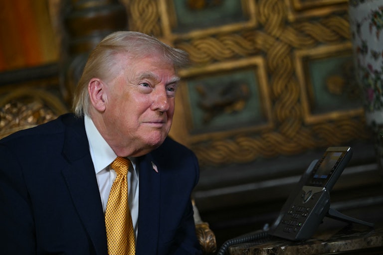 Donald Trump smiles creepily in front of some paintings at Mar-a-Lago.