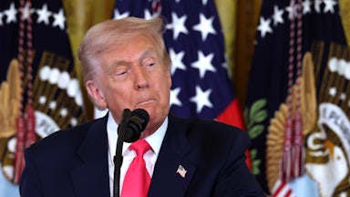 Donald Trump pulls the corners of his mouth down as he stands at a microphone