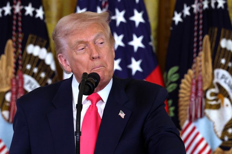 Donald Trump pulls the corners of his mouth down as he stands at a microphone