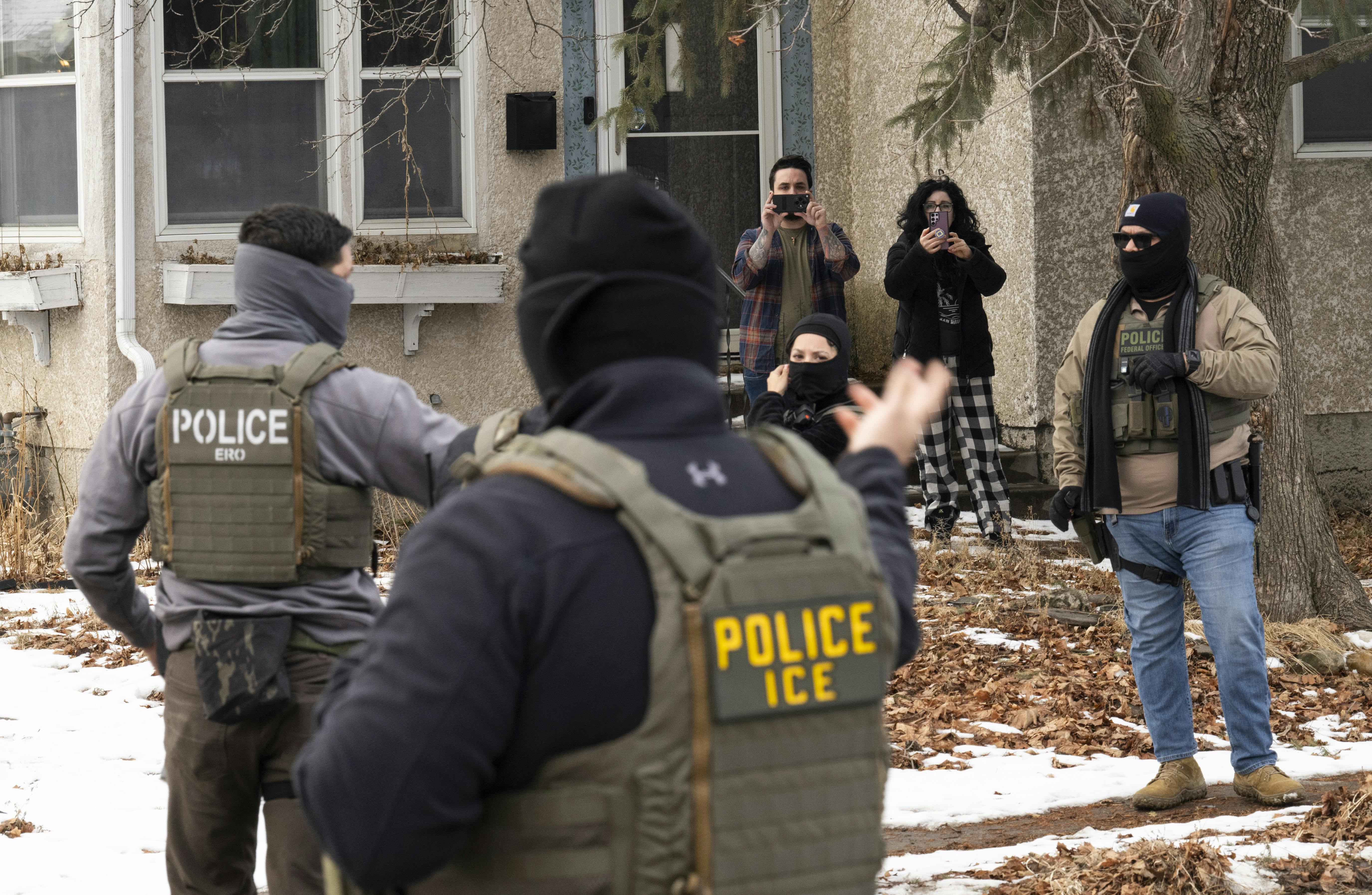 Observers film masked ICE agents outside a suburban home.