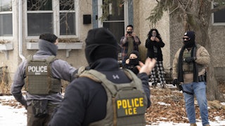 Observers film masked ICE agents outside a suburban home.