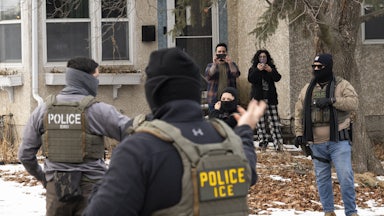Observers film masked ICE agents outside a suburban home.