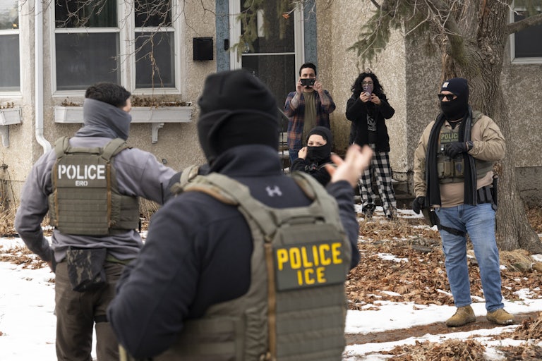 Observers film masked ICE agents outside a suburban home.