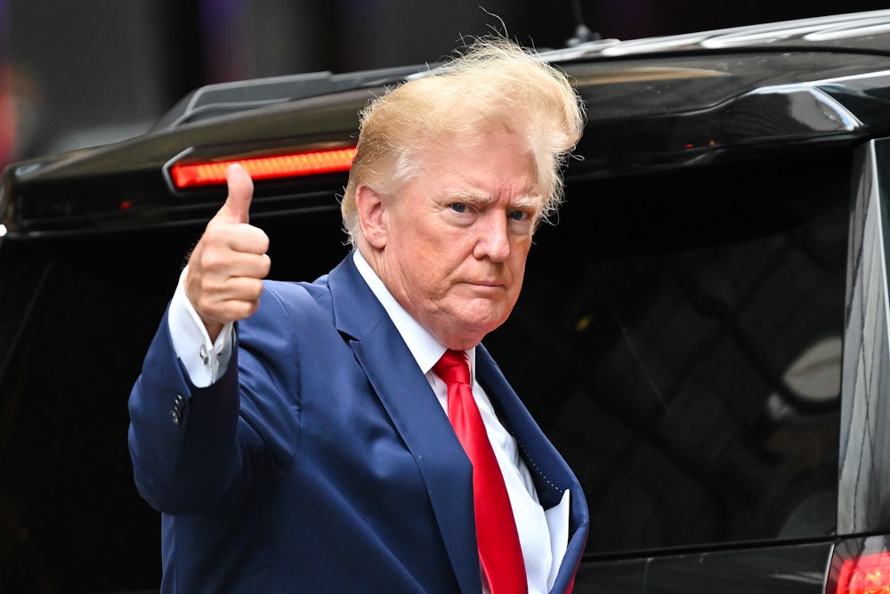 Donald Trump gives a thumbs up with wind blowing his hair.