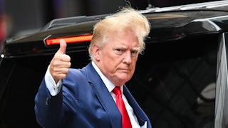 Donald Trump gives a thumbs up with wind blowing his hair.