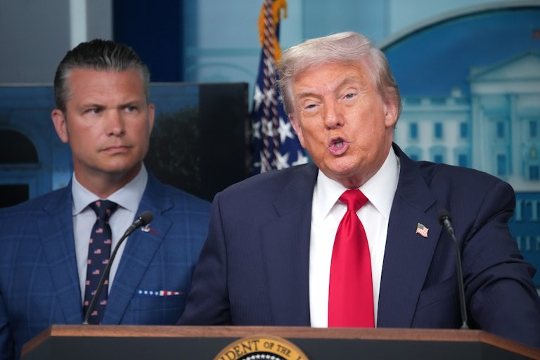 Donald Trump speaks in the White House press briefing room while Defense Secretary Pete Hegseth stands behind him