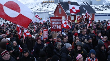 Protesters hold Greenlandic flags and signs that read things like "Greenland Is Not For Sale!"