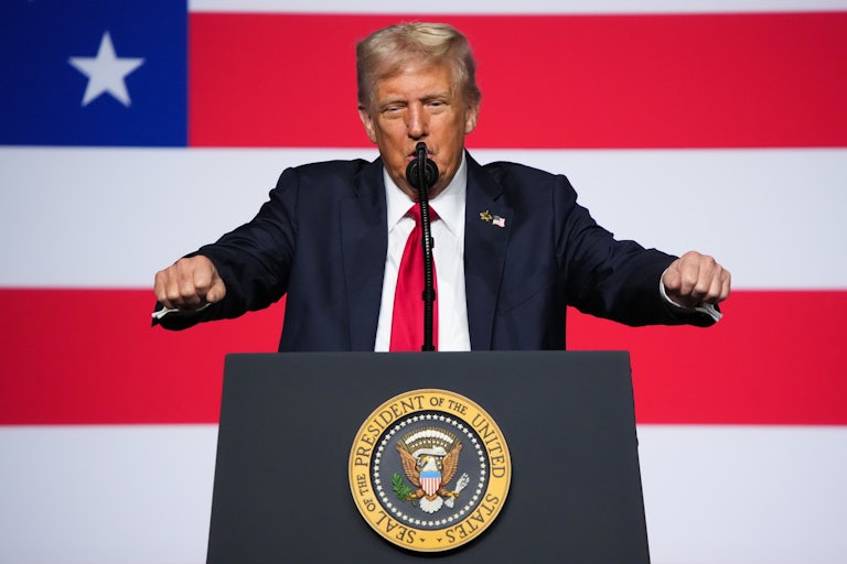 Donald Trump holds his fists in front of himself while speaking to military leaders at Quantico