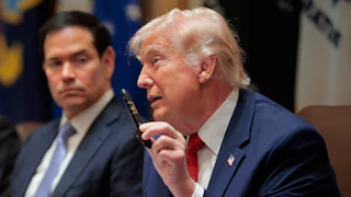 President Donald Trump holds up a Sharpie as he speaks. Secretary of State Marco Rubio, sitting next to him, looks on.