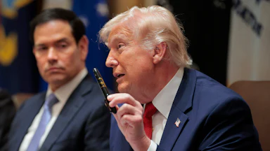 President Donald Trump holds up a Sharpie as he speaks. Secretary of State Marco Rubio, sitting next to him, looks on.