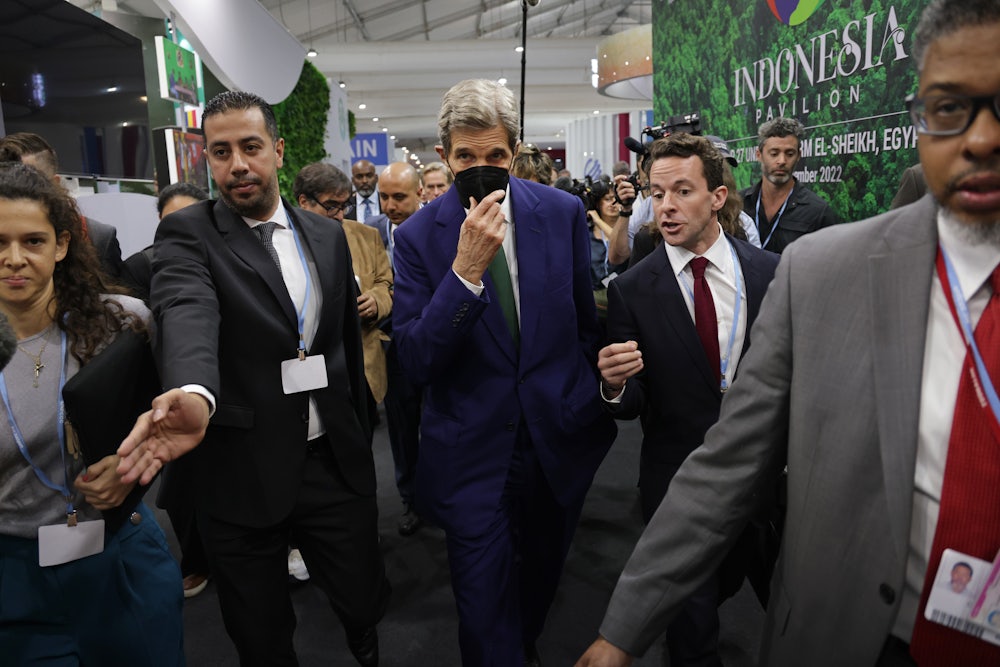 John Kerry walks in a throng of people.