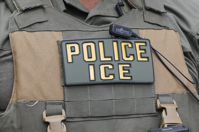 An Immigration and Customs Enforcement officer wears a patch on their vest that says "Police ICE"