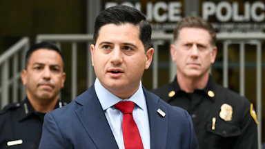 First Assistant U.S. Attorney for the Central District of California Bill Essayli speaks with two police officers behind him