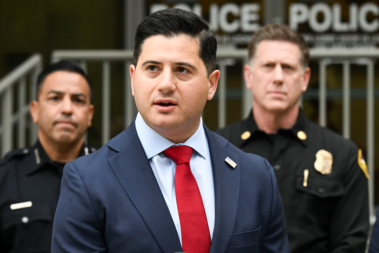 First Assistant U.S. Attorney for the Central District of California Bill Essayli speaks with two police officers behind him