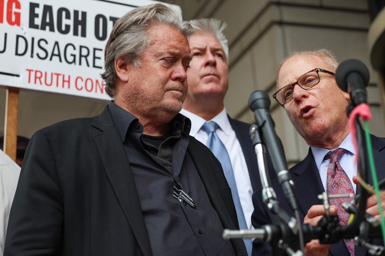 David Schoen speaks into microphones as he stands next to Steve Bannon