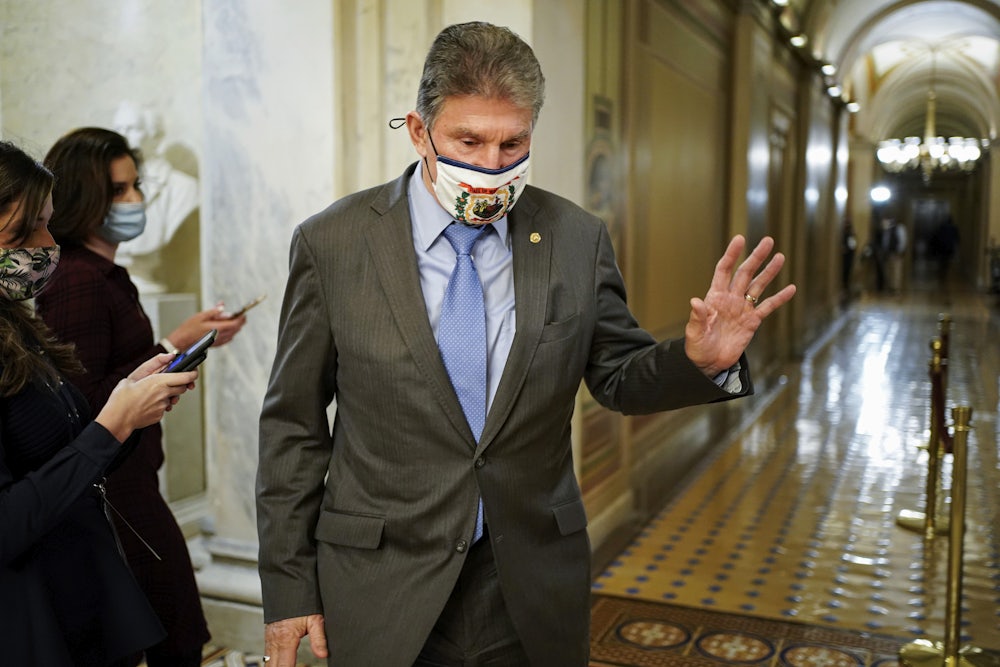 A masked Joe Manchin passes by reporters as he departs Capitol Hill.
