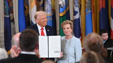 Donald Trump holds a signed executive order as he poses alongside Education Secretary Linda McMahon.