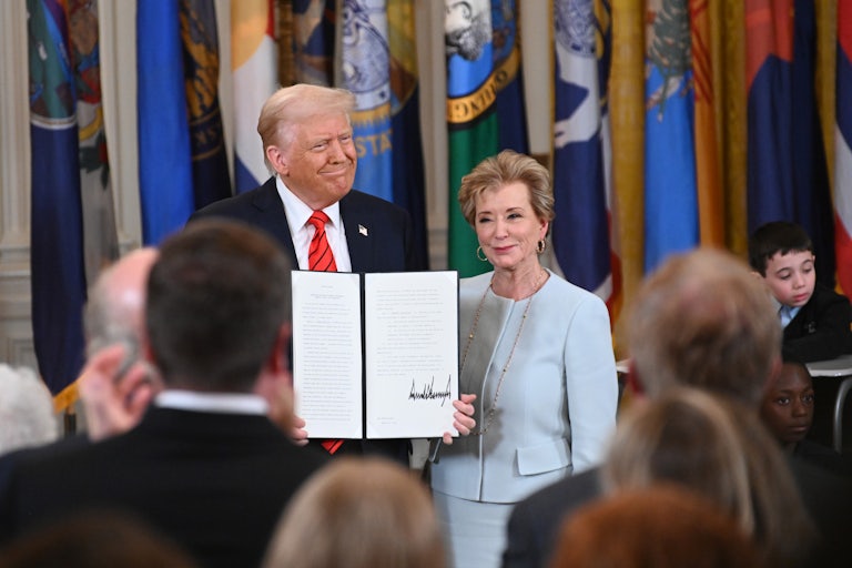 Donald Trump holds a signed executive order as he poses alongside Education Secretary Linda McMahon.
