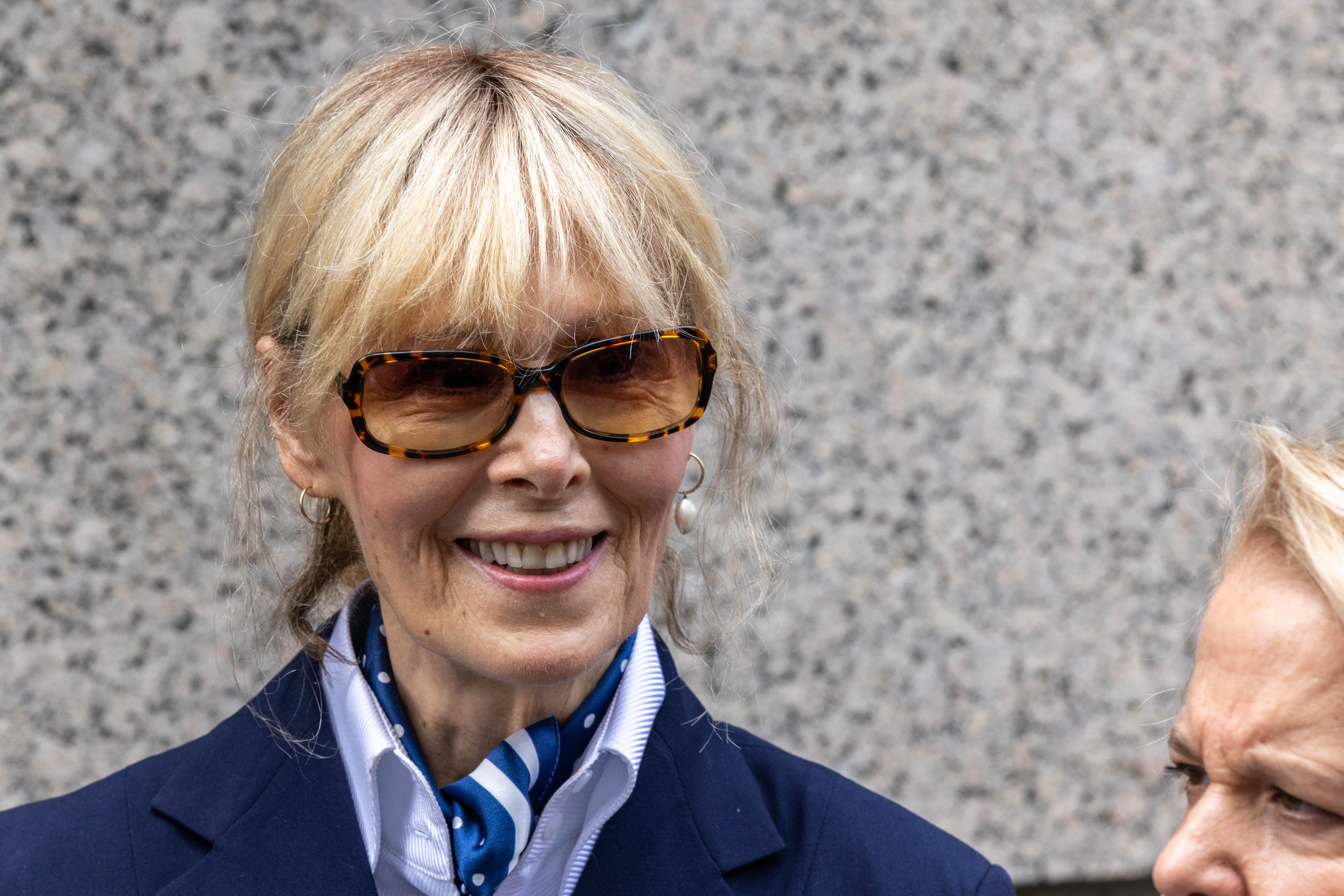 E. Jean Carroll smiles while walking out of a New York City courthouse