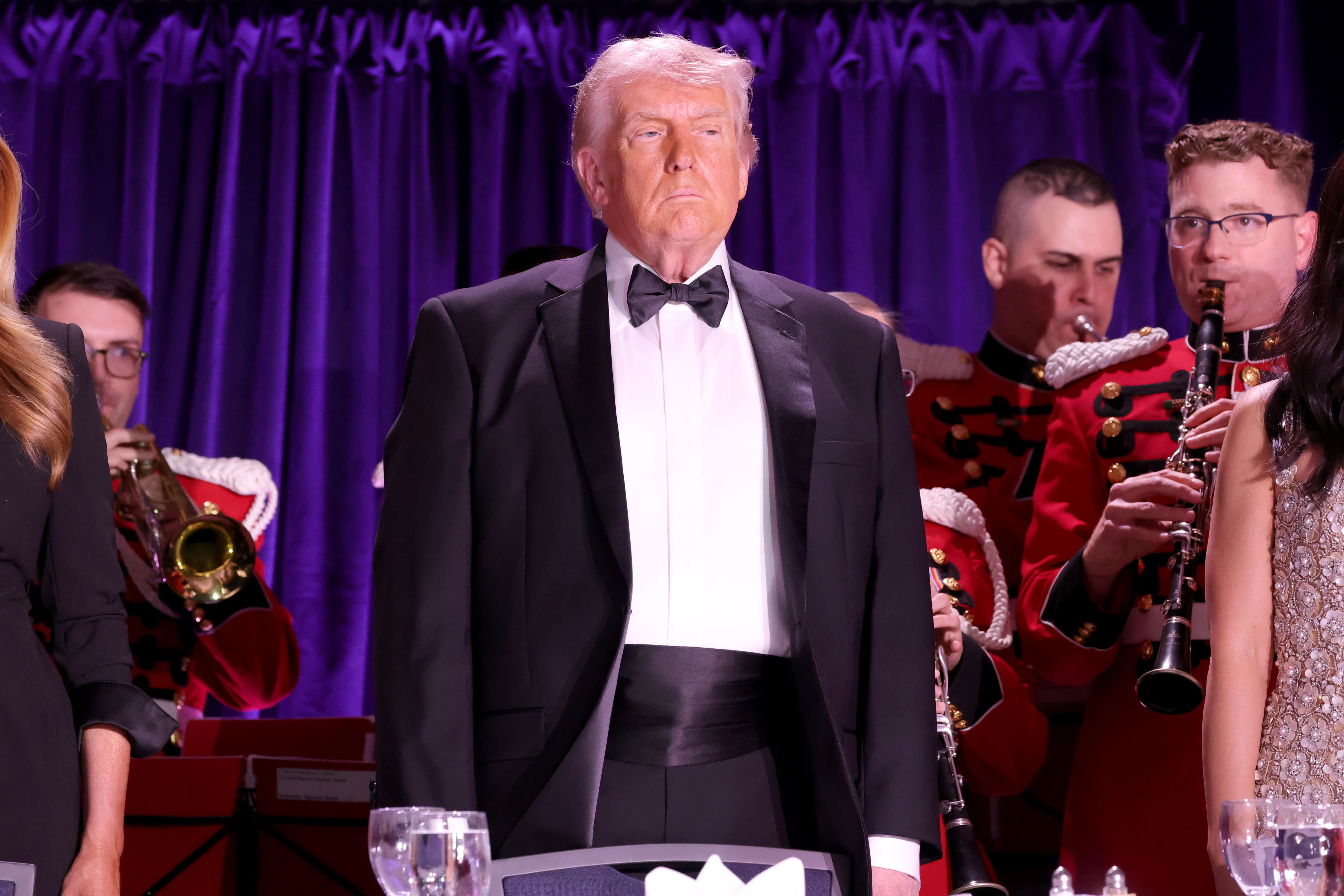 President Donald Trump stands and looks on at the White House Correspondents Dinner.