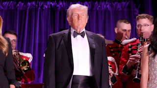 President Donald Trump stands and looks on at The White House Correspondents Dinner,