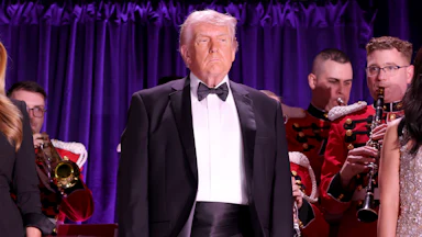 President Donald Trump stands and looks on at the White House Correspondents Dinner.