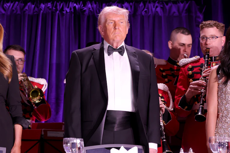 President Donald Trump stands and looks on at the White House Correspondents Dinner.