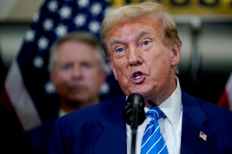 Donald Trump speaking on a mic, eyebrows raised