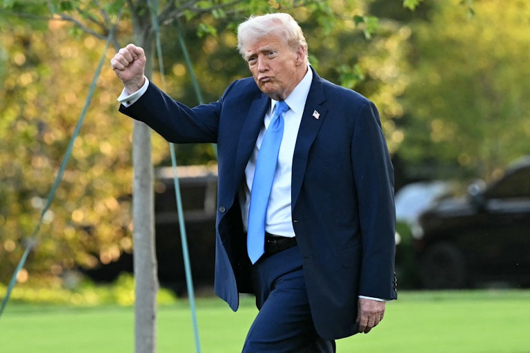 Donald Trump puckers his lips and raises his fist while walking outside the White House