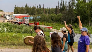 People raise their fists in front of a construction site.