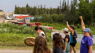 People raise their fists in front of a construction site.