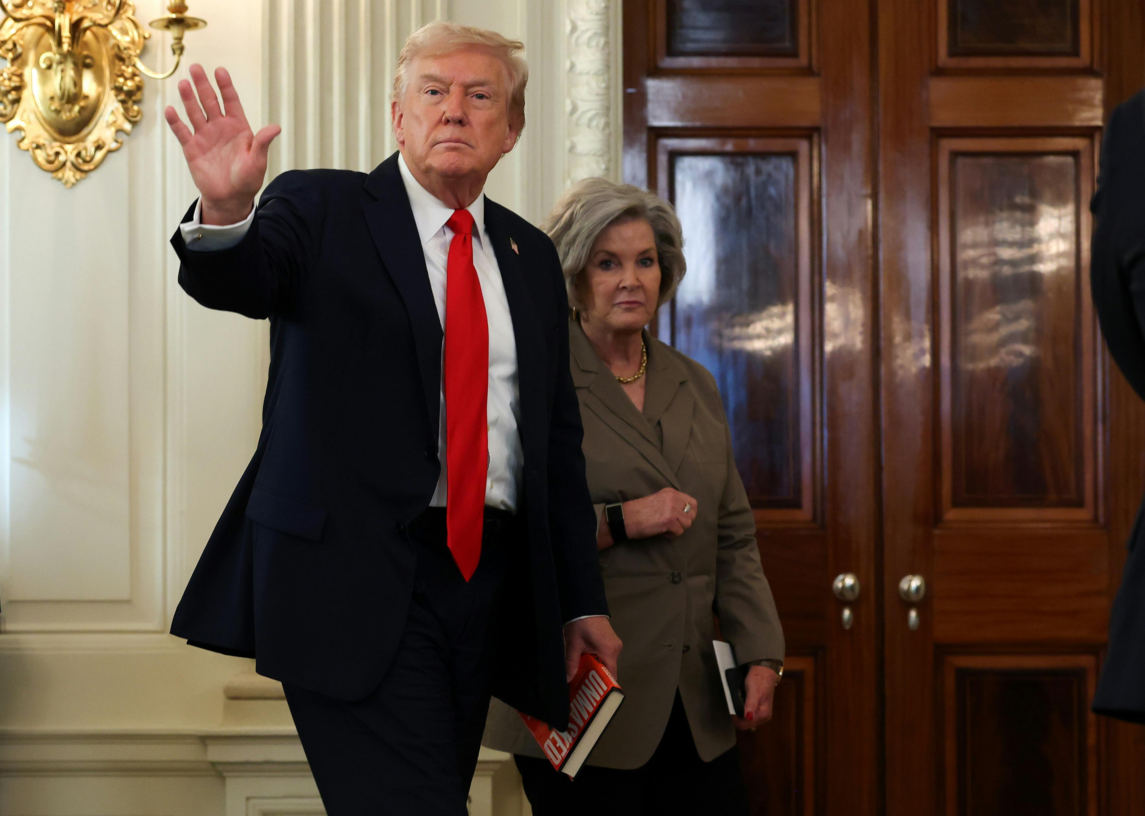 Donald Trump waves while walking in front of his chief of staff Susie Wiles