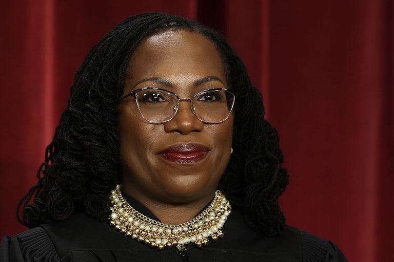 Ketanji Brown Jackson smiles in front of a red curtain