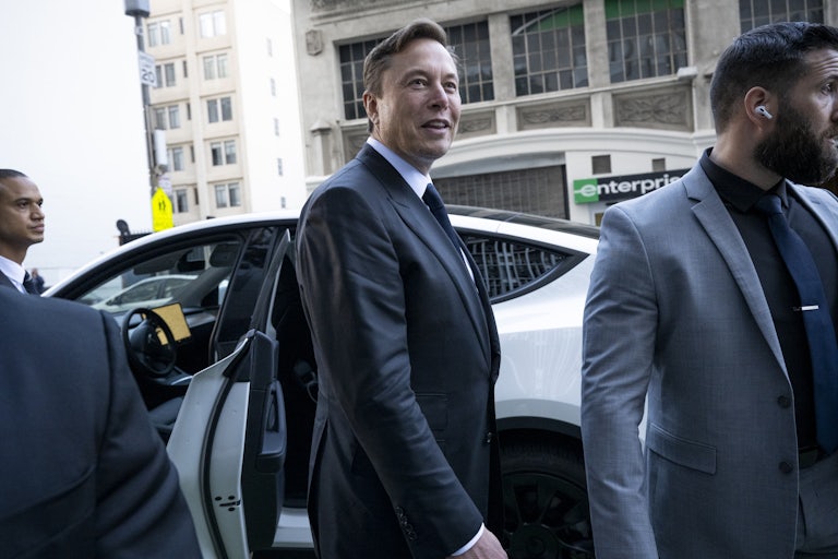 Elon Musk stands near a Tesla outside