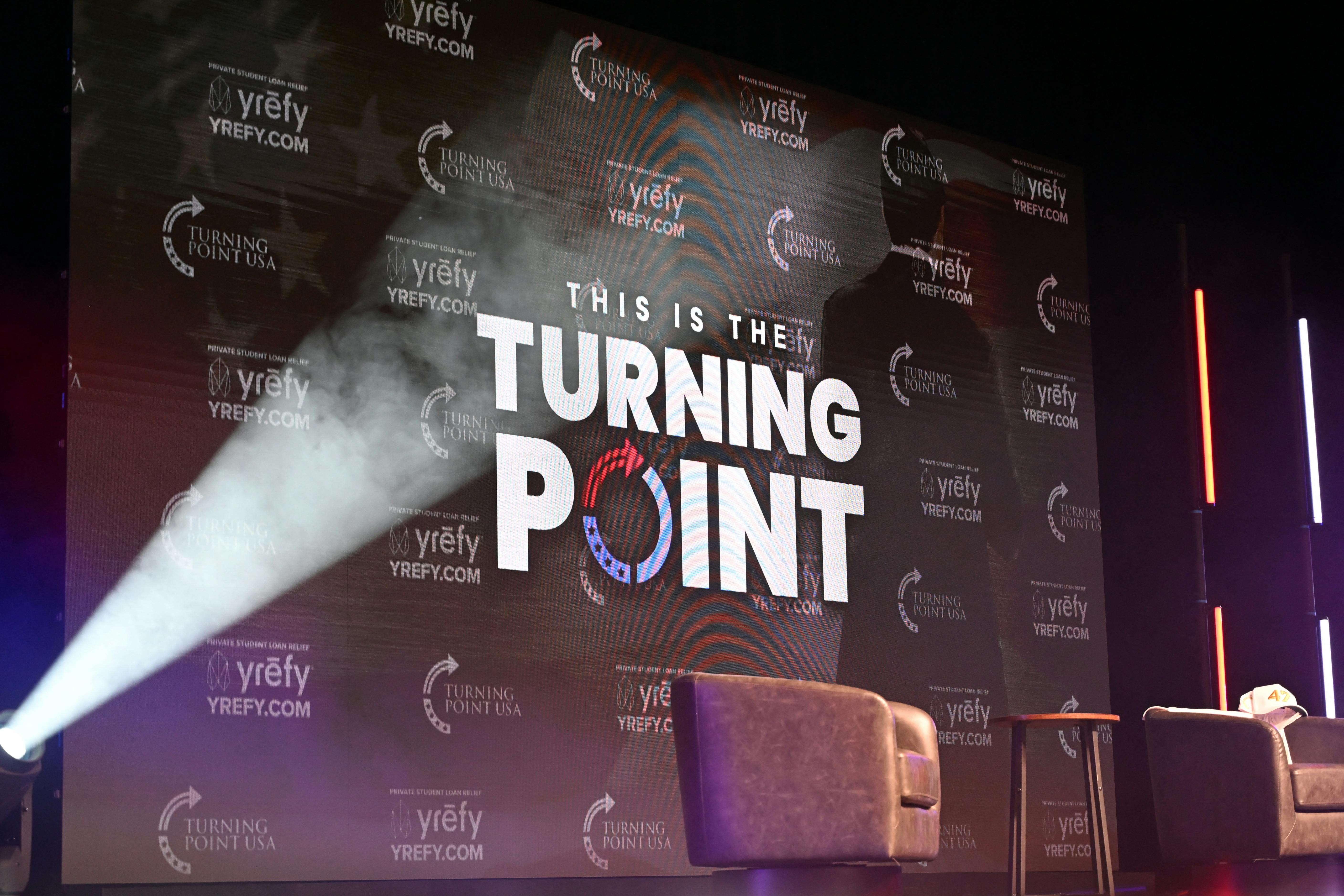 The Turning Point USA logo is projected onto an onstage screen