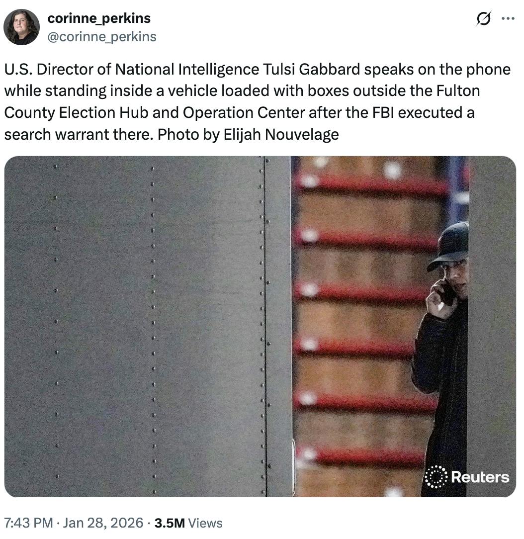 X screenshot corinne_perkins @corinne_perkins U.S. Director of National Intelligence Tulsi Gabbard speaks on the phone while standing inside a vehicle loaded with boxes outside the Fulton County Election Hub and Operation Center after the FBI executed a search warrant there. Photo by Elijah Nouvelage (Reuters photo of Tulsi Gabbard speaking on the phone as she peeks behind a door)