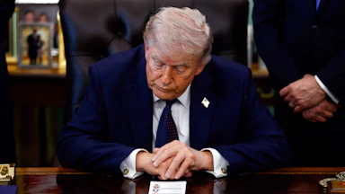 Donald Trump leans forward on his desk in the Oval Office with his eyes closed