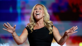 Marjorie Taylor Greene holds her arms out while smiling.
