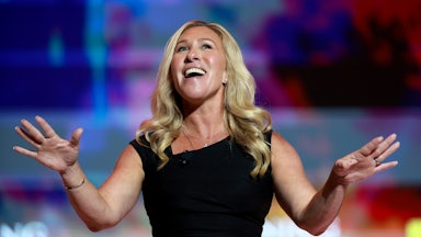 Marjorie Taylor Greene holds her arms out while smiling.