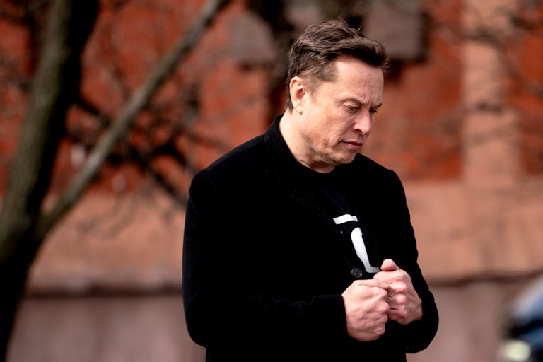 Elon Musk walks outside and clenches both his fists next to each other
