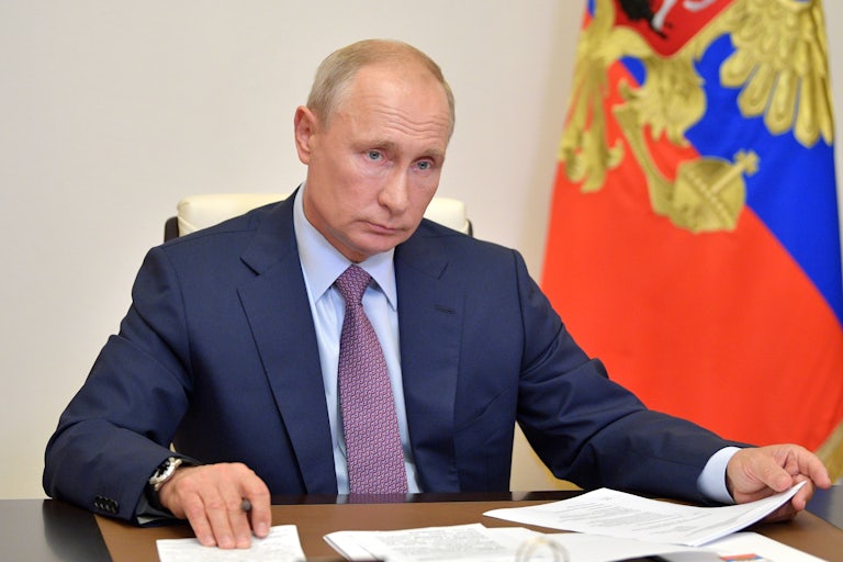 Vladimir Putin shuffles papers on his desk as he chairs a meeting.