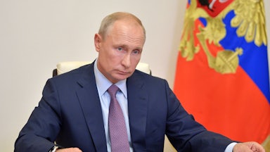 Vladimir Putin shuffles papers on his desk as he chairs a meeting.